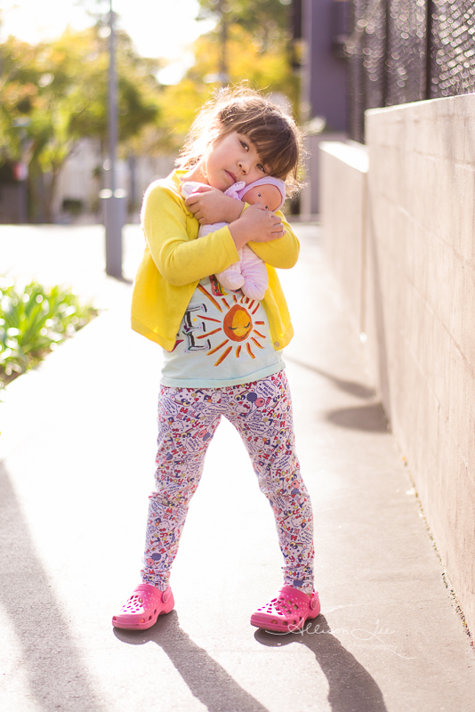 brown haired girl with baby doll in sunshine