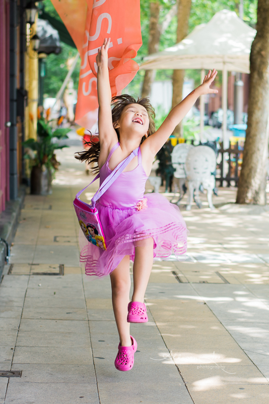 Portrait of girl jumping for joy in purple dress